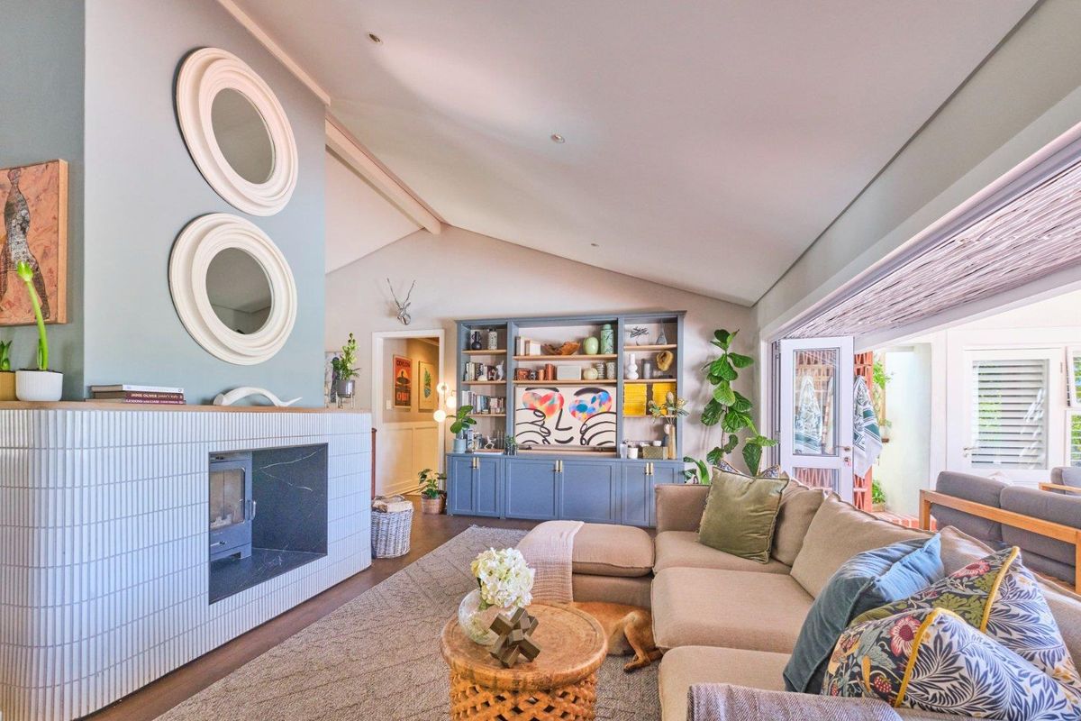 Spacious living room featuring a modern tiled fireplace, built-in cabinetry, vaulted ceilings, and seamless access to the outdoor area through bi-fold doors.