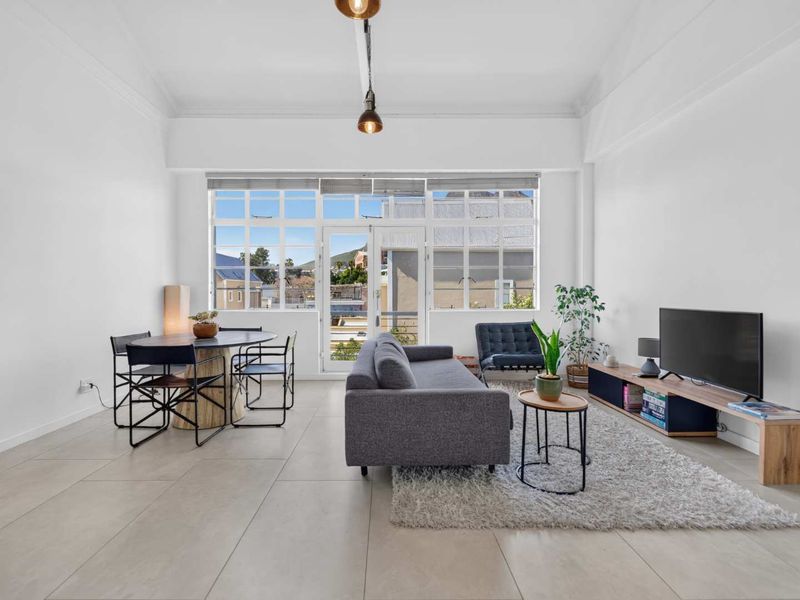Bright and spacious living area featuring high ceilings, large multi-pane windows, and neutral tiled flooring, offering a clean and modern aesthetic.