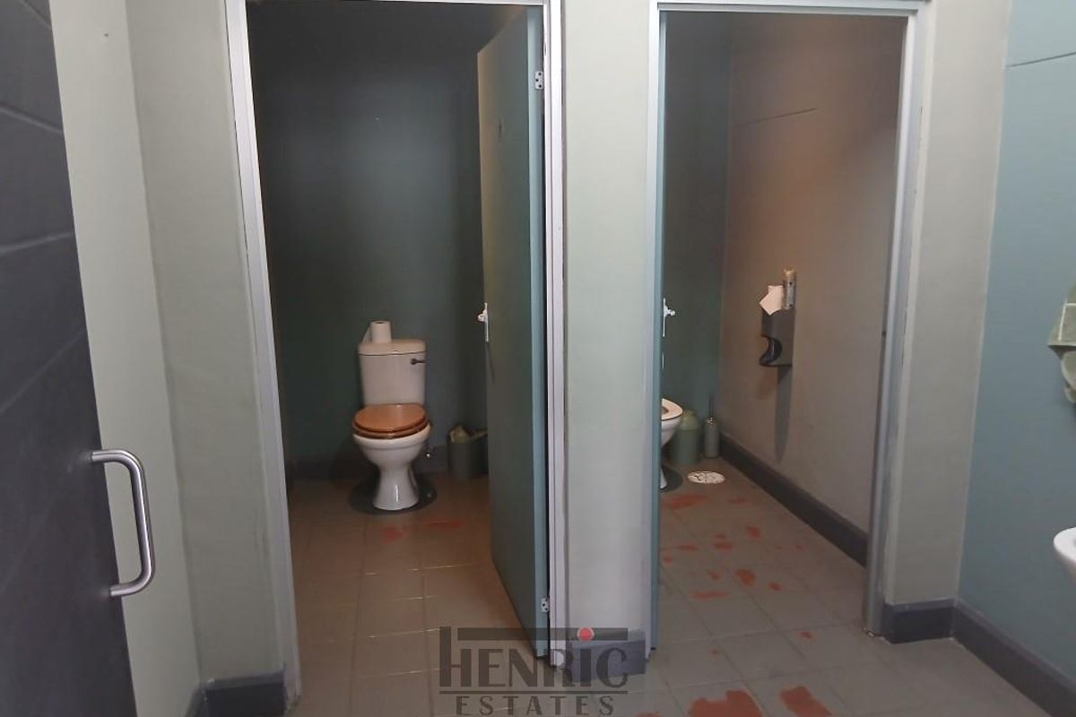 A functional bathroom facility featuring two separate toilet cubicles with tiled flooring and basic sanitary fixtures.