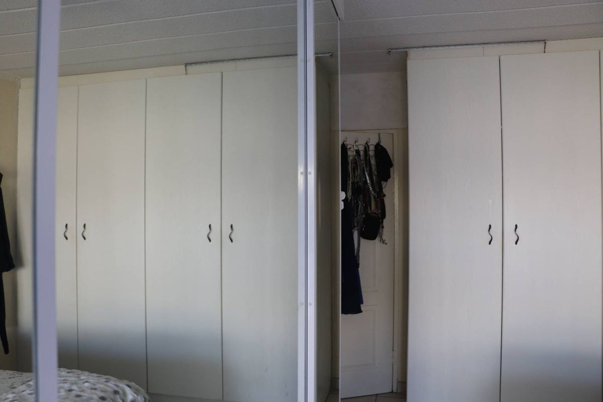 Bedroom featuring extensive built-in wardrobes with integrated mirrored panels, providing ample storage space.