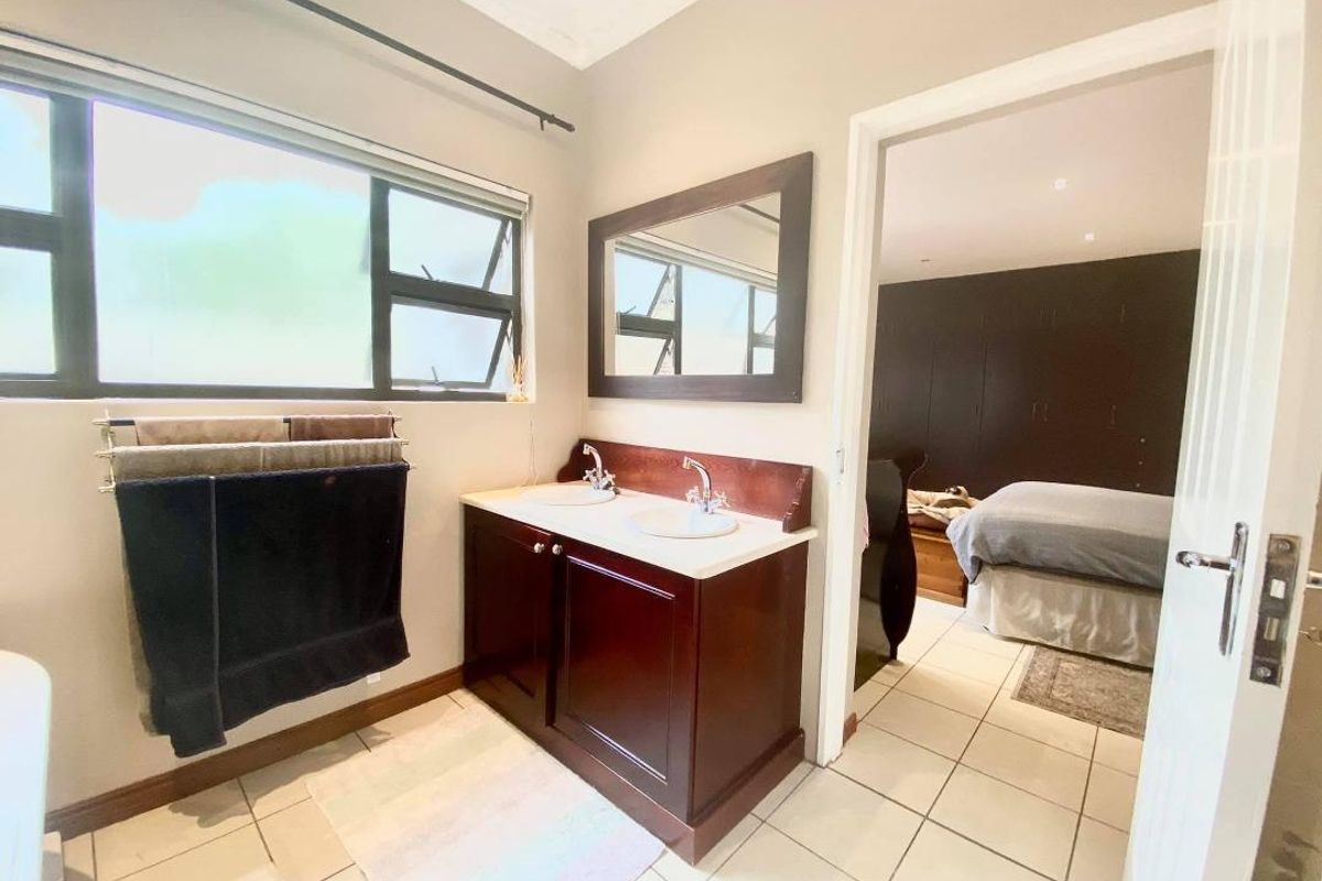 A functional bathroom featuring a double vanity with dark wood cabinetry, tiled flooring, and a large window providing natural light.