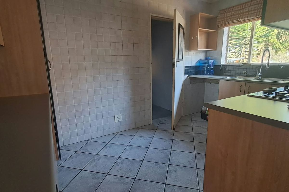 A functional kitchen featuring built-in cabinetry, a gas hob, tiled splashbacks, and tiled flooring, offering a practical layout ready for modernization.