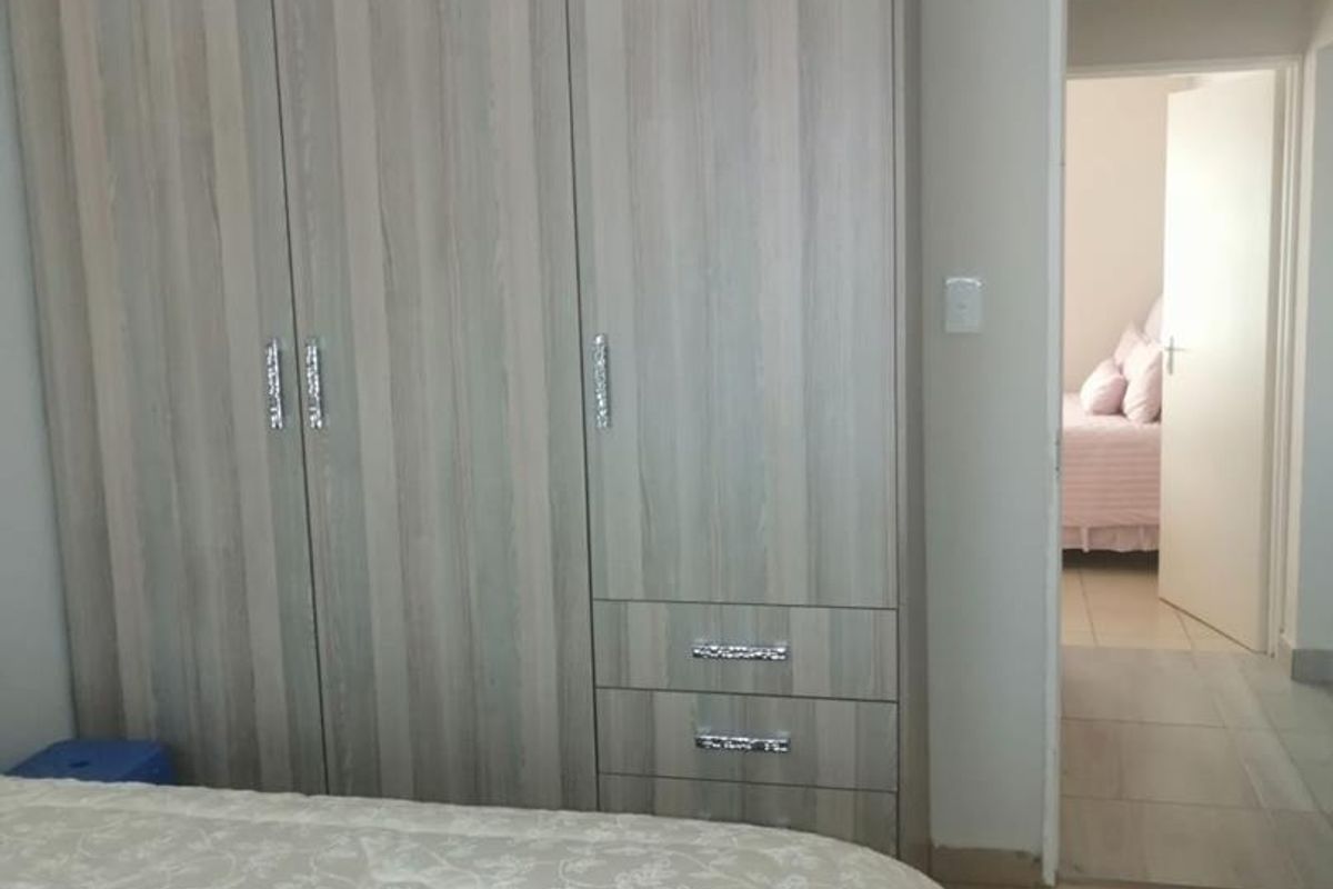 A bedroom featuring built-in wooden cabinetry with integrated drawers and a doorway leading to an adjacent room.