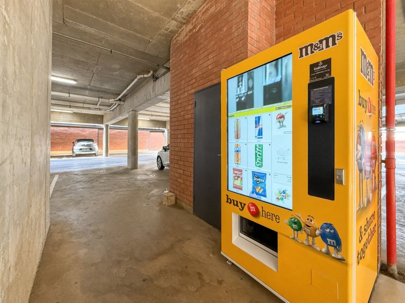 A functional concrete parking garage area featuring exposed brickwork, support columns, and overhead fluorescent lighting, providing secure covered parking space.