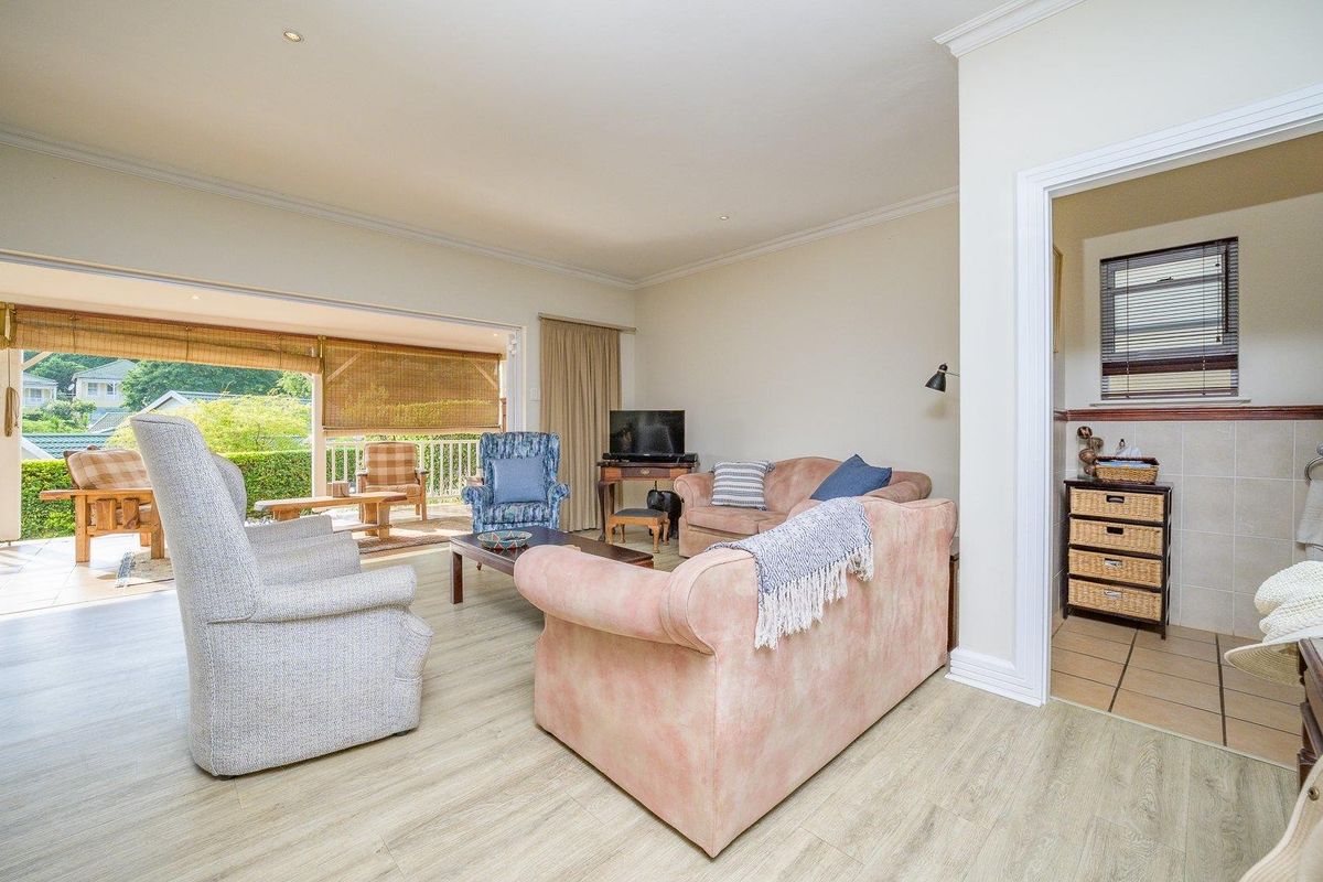 Spacious living room featuring light laminate flooring, crown molding, and large sliding doors providing seamless access to the covered patio area.