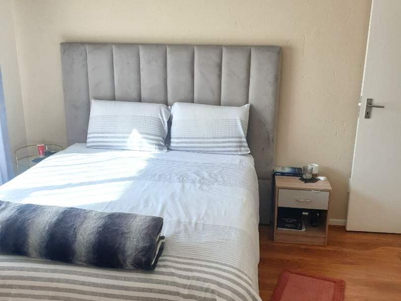 A bedroom featuring laminate wood flooring and a neutral wall finish, providing a simple and functional sleeping space.