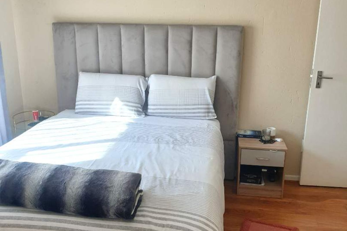 A bedroom featuring laminate wood flooring and a neutral wall finish, providing a simple and functional sleeping space.