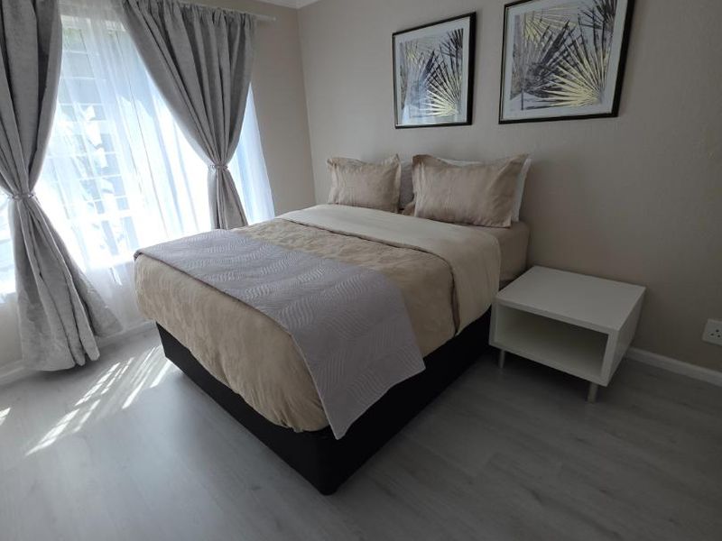 A well-maintained bedroom featuring light-toned laminate flooring, neutral wall finishes, and classic cove cornicing, offering a clean and comfortable living space.