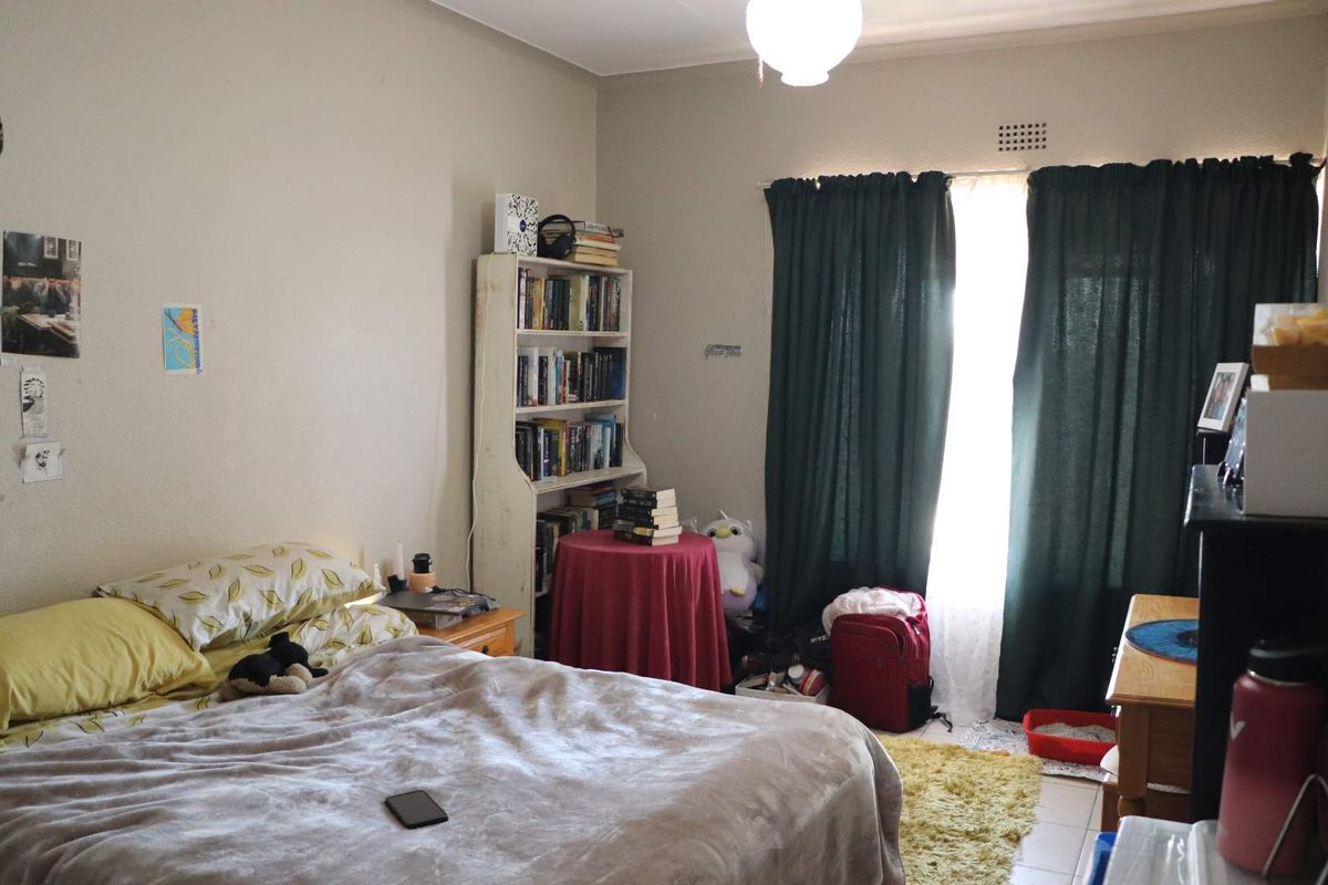 A bedroom featuring tiled flooring, a window with curtain tracks, and a ceiling-mounted light fixture.