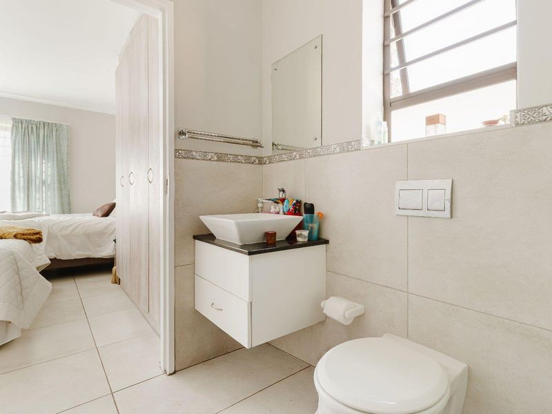 A modern bathroom featuring a wall-mounted vanity with a vessel sink, wall-hung toilet with concealed cistern, and neutral tiled finishes.