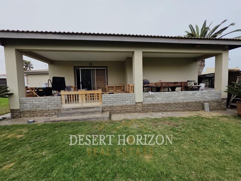 A covered outdoor patio area featuring brick base detailing and direct access to the garden through sliding glass doors.