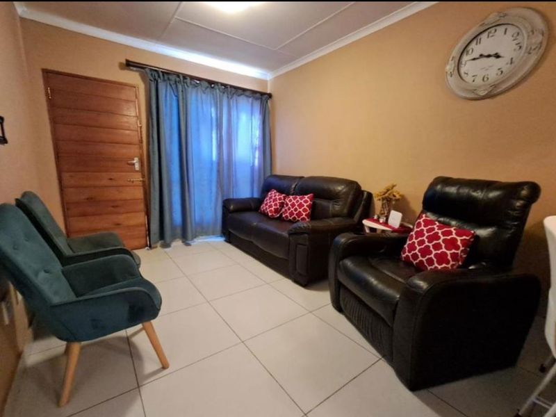 A living room area featuring tiled flooring, a timber door, and cove cornicing, providing a functional space for relaxation.