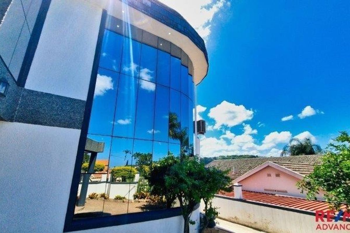 Rear elevation of the property featuring modern floor-to-ceiling glass curtain walling and a clean plastered exterior finish.