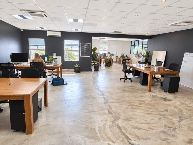 Spacious open-plan office area featuring polished concrete floors, suspended ceiling with recessed lighting, and integrated air conditioning units.