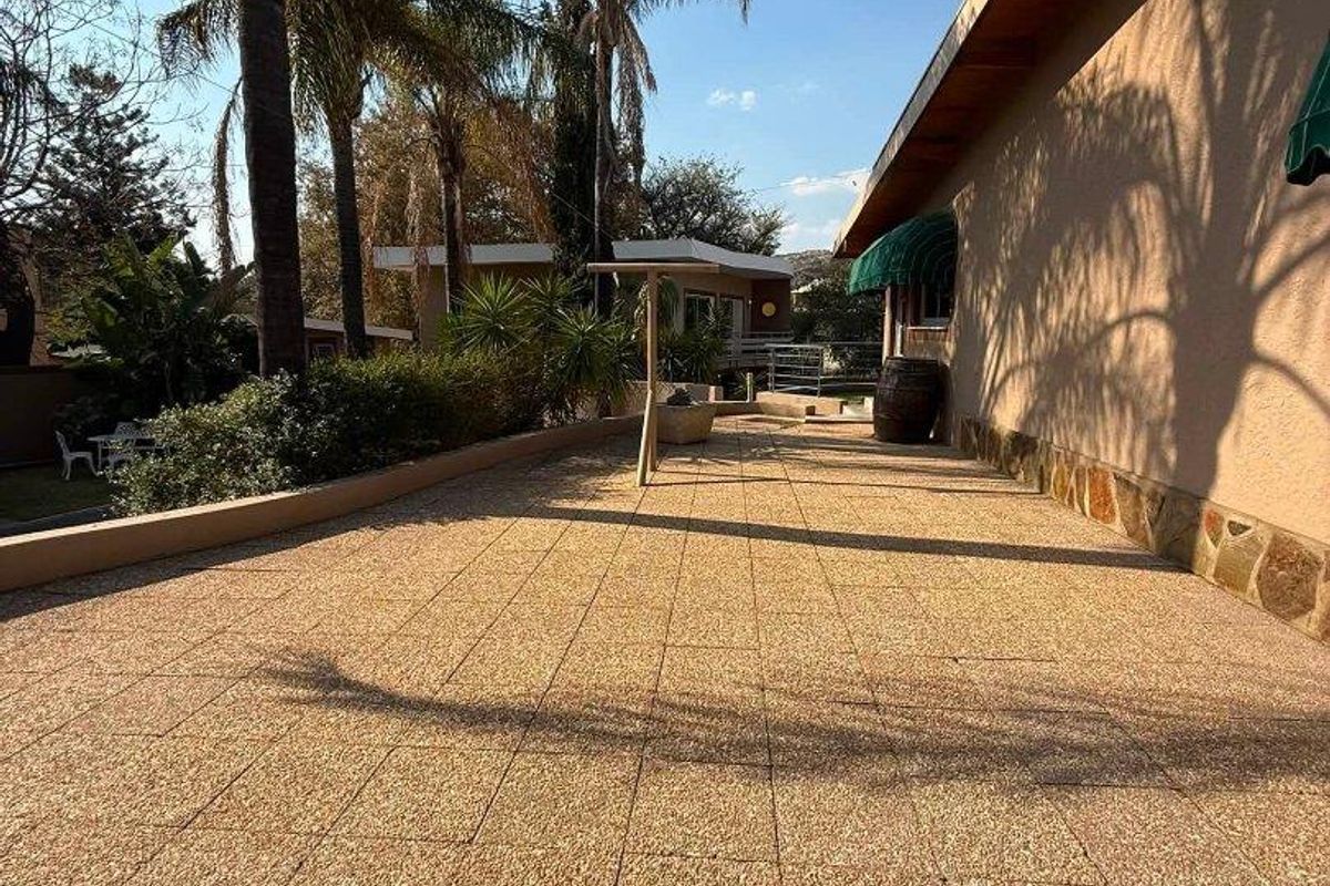 A spacious outdoor patio area featuring paved flooring, stone wall accents, and an awning, providing a functional space for outdoor living.
