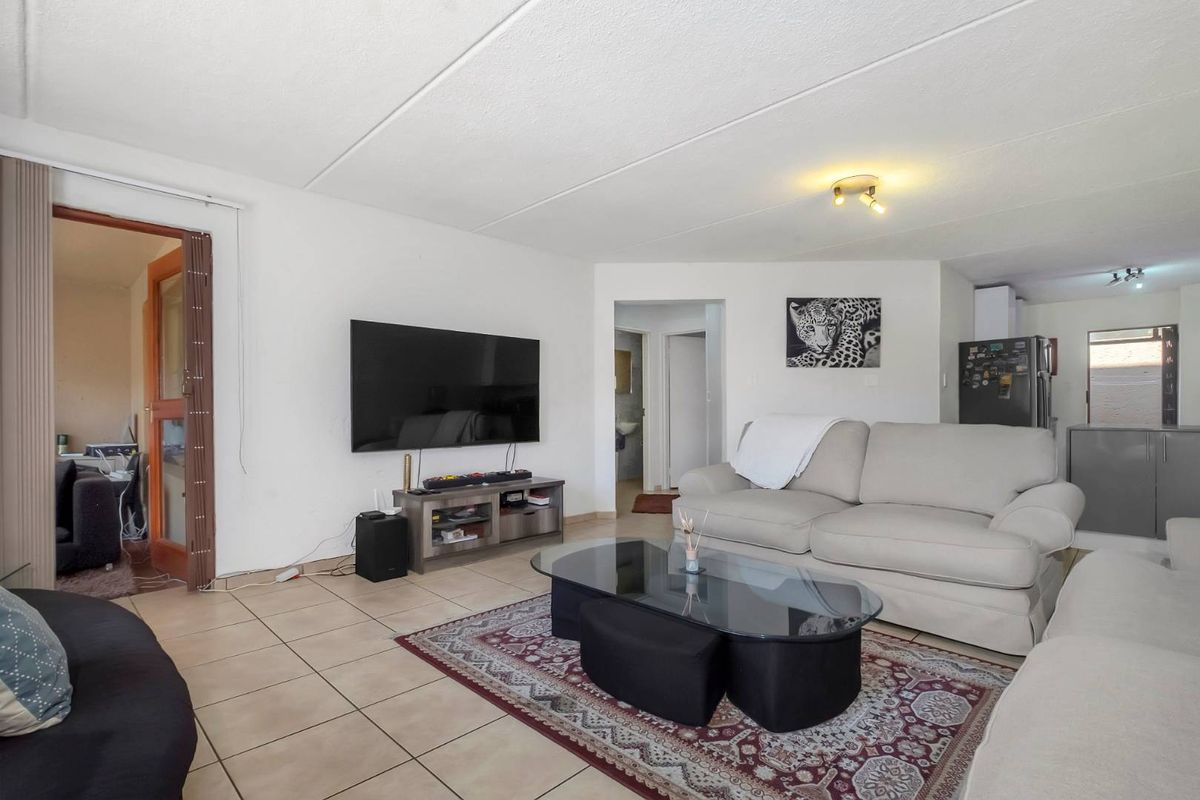 A spacious living room featuring tiled flooring and neutral walls, providing a functional and open layout for comfortable daily living.
