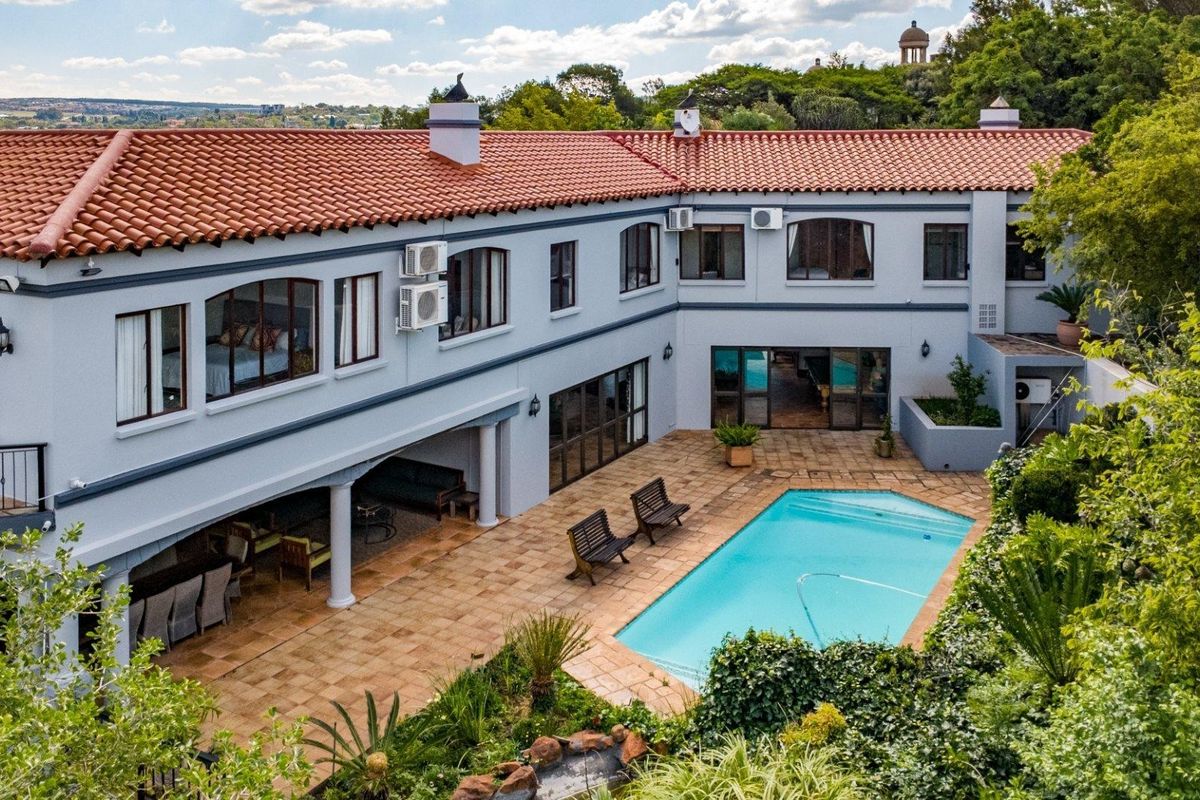 Aerial view of a spacious rear courtyard featuring a swimming pool, covered patio area, and well-maintained landscaping against the two-story residence.