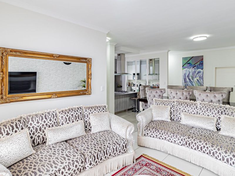 Spacious open-plan living area featuring tiled floors and a modern kitchen with integrated cabinetry and built-in appliances.
