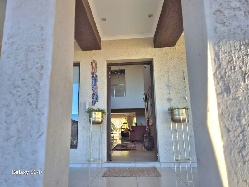 A welcoming covered entrance area featuring tiled flooring and architectural ceiling beams, providing a clear view into the home's interior living space.