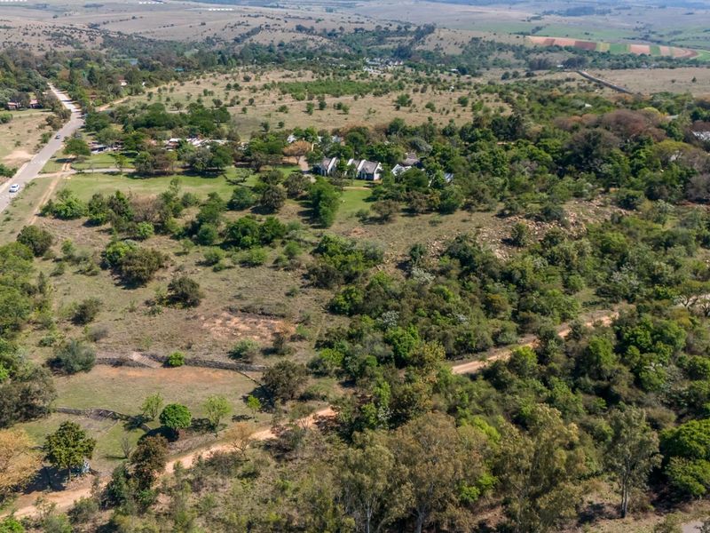 Aerial view of a large small holding property featuring extensive natural vegetation, established trees, and convenient access via paved and gravel roads.