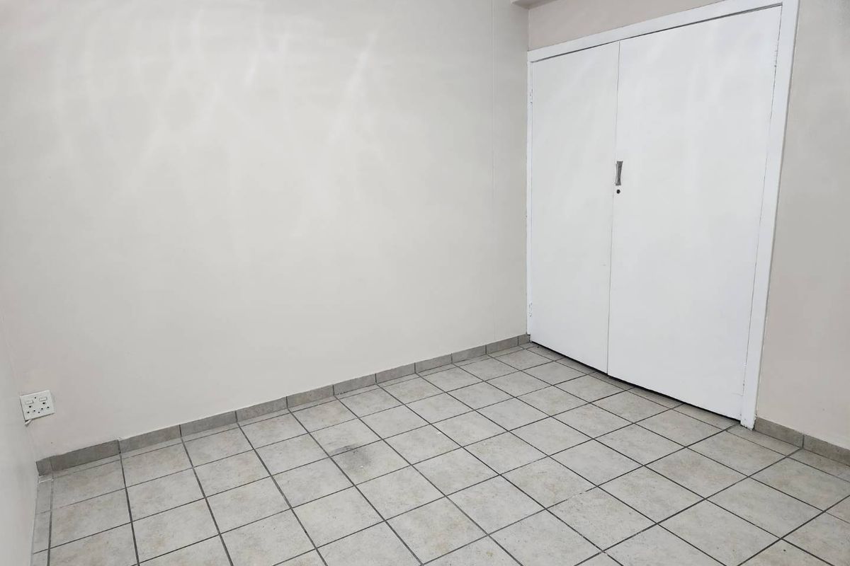 An empty bedroom featuring tiled flooring and a built-in cupboard, providing a blank canvas for potential interior design updates.