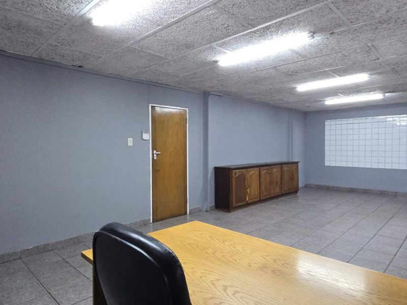 Functional office space featuring tiled flooring, suspended ceiling with fluorescent lighting, and built-in cabinetry, suitable for a professional industrial or commercial workspace.