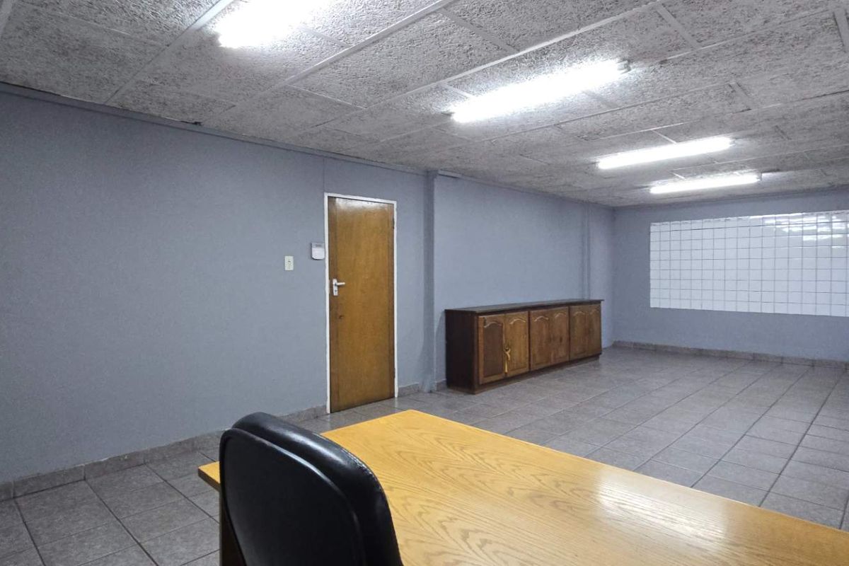 Functional office space featuring tiled flooring, suspended ceiling with fluorescent lighting, and built-in cabinetry, suitable for a professional industrial or commercial workspace.