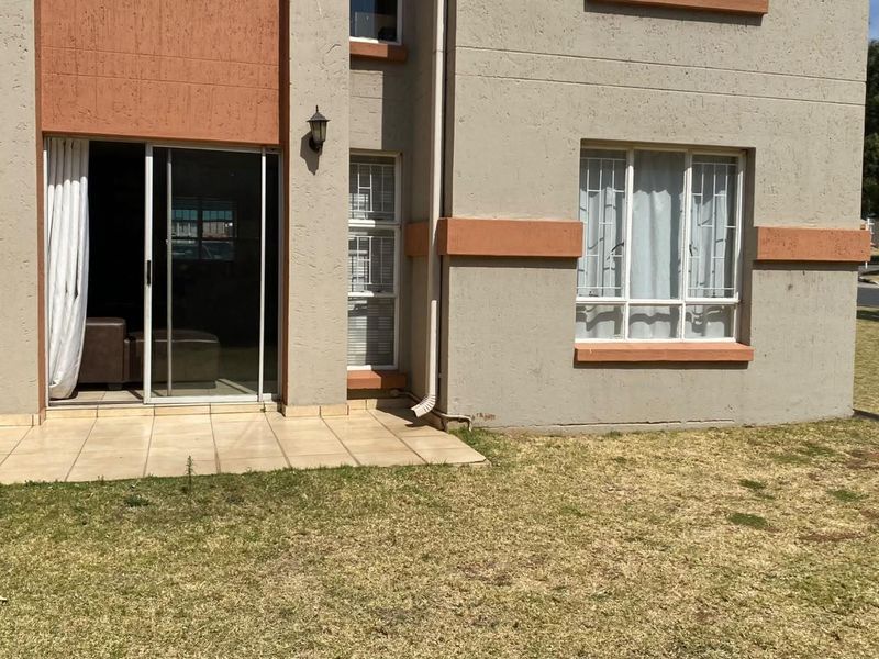 Rear view of the apartment featuring a small tiled patio, sliding glass door access, and security bars on the windows.