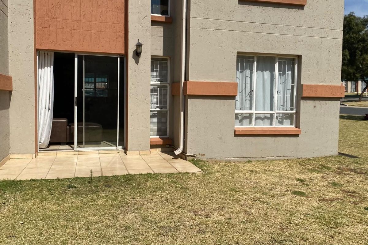 Rear view of the apartment featuring a small tiled patio, sliding glass door access, and security bars on the windows.