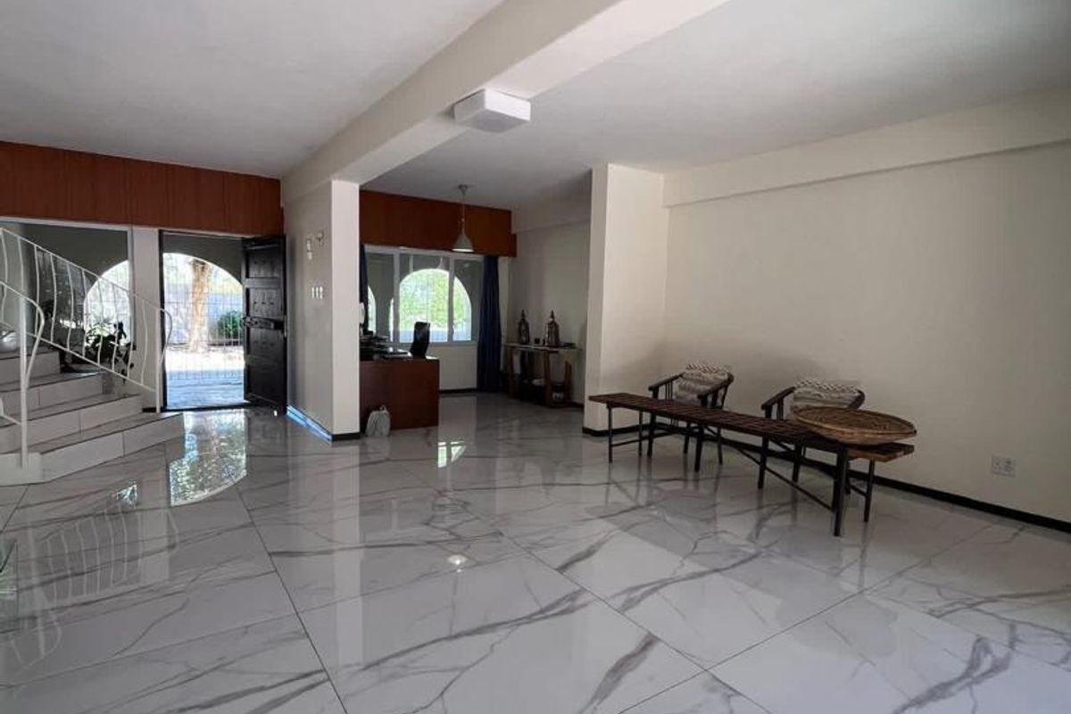 Spacious living area featuring large-format marble-look floor tiles, a distinctive spiral staircase, and arched windows providing natural light.