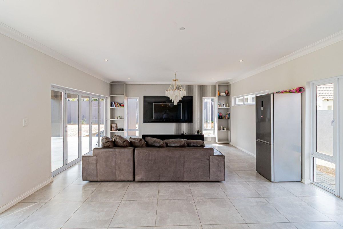 Spacious living area featuring large format floor tiles, built-in shelving units, and expansive sliding glass doors providing seamless access to the outdoor patio.