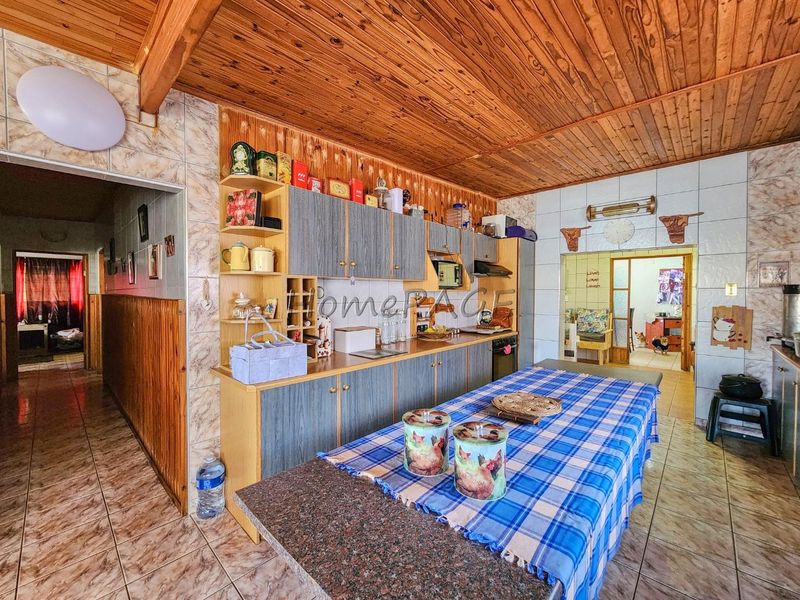A functional kitchen featuring built-in cabinetry, granite countertops, and a distinctive wood-panelled ceiling, offering a traditional layout with tiled finishes throughout.