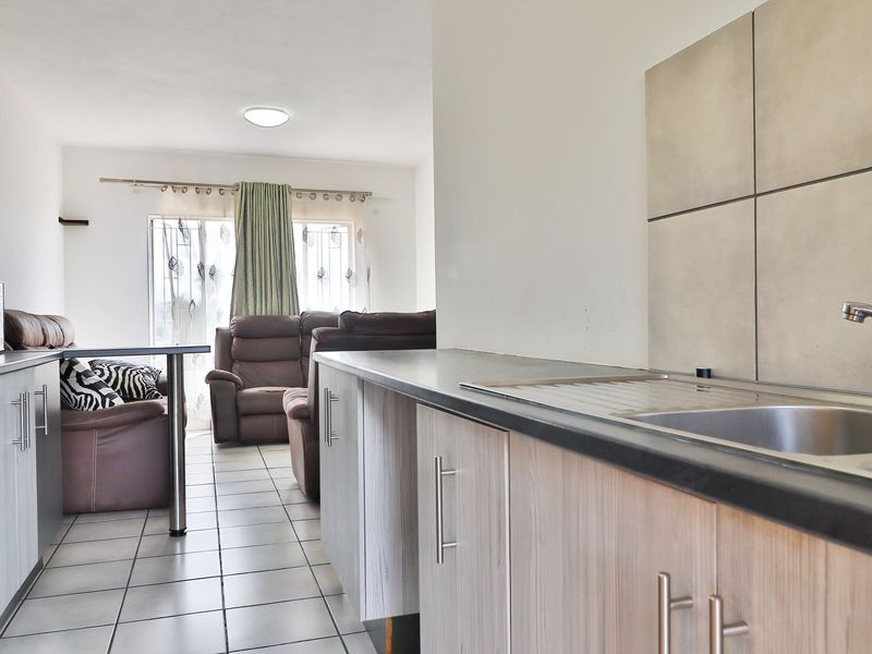 Open plan kitchen and living area featuring tiled flooring, modern cabinetry, and a functional kitchen layout with built-in appliances.