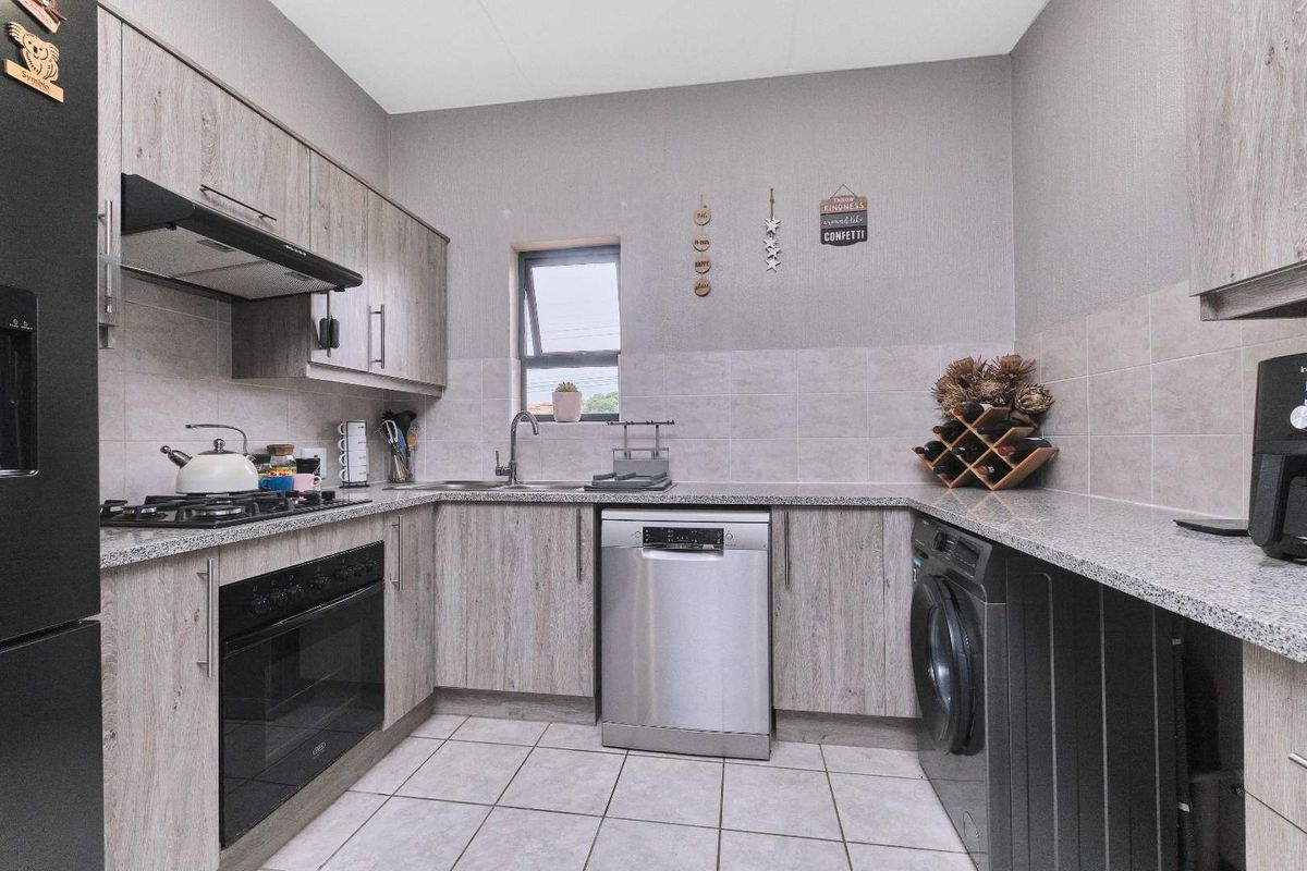 A functional kitchen featuring wood-look cabinetry, granite countertops, a built-in oven, gas hob, extractor fan, and space for under-counter appliances.