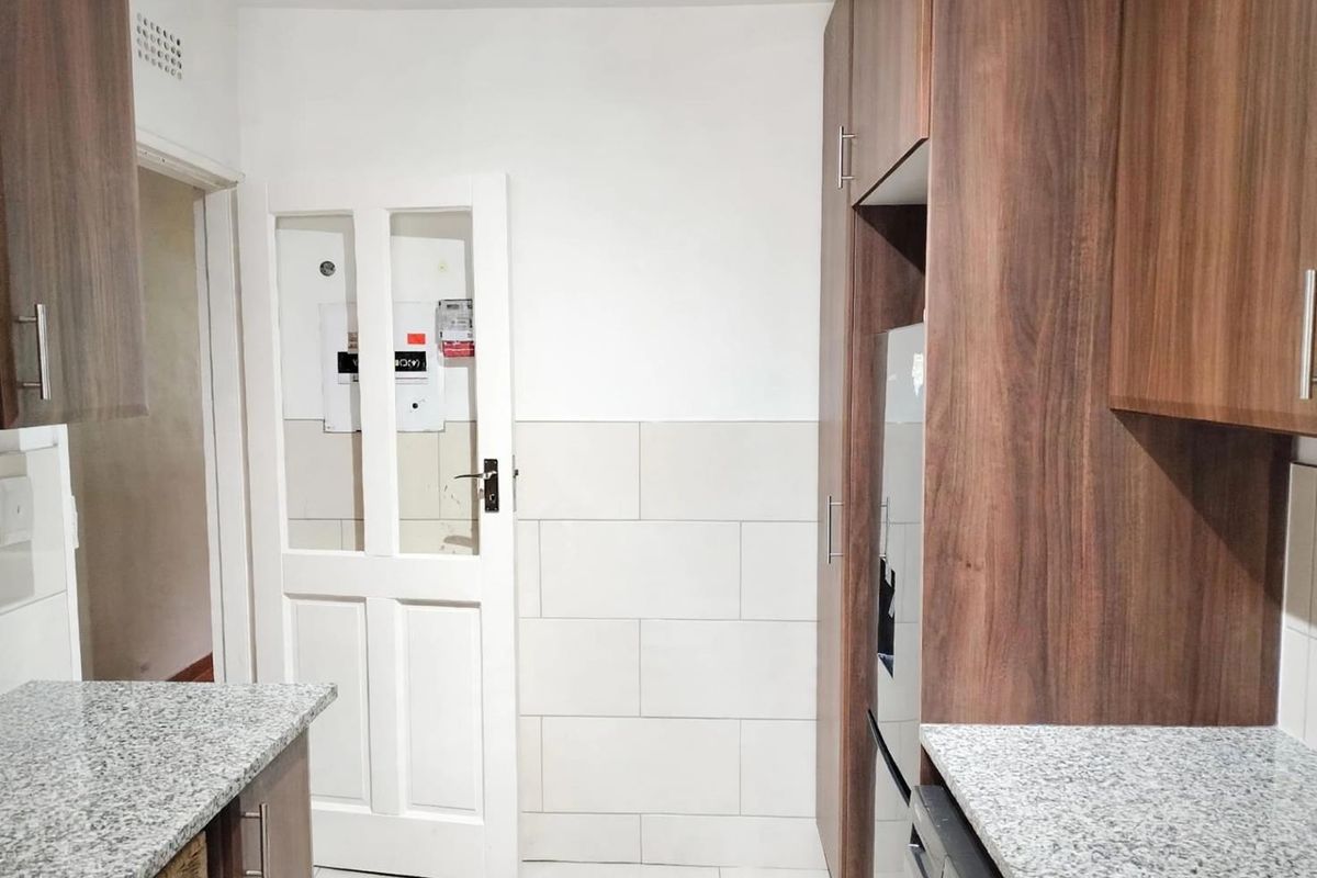 A functional kitchen featuring modern wood-look cabinetry, granite countertops, and neutral tiled splashbacks, providing a clean and practical workspace.