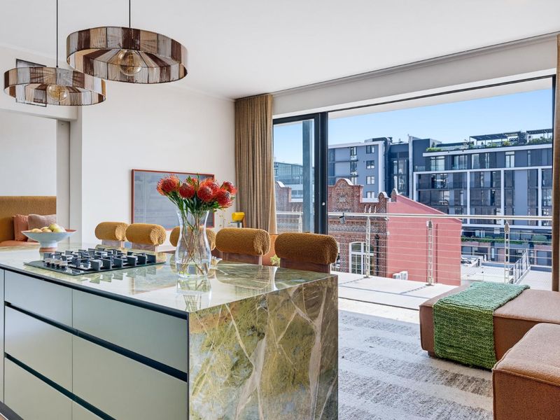 Modern open-plan living area featuring a premium stone kitchen island with integrated cooktop and seamless access to a private balcony with urban views.