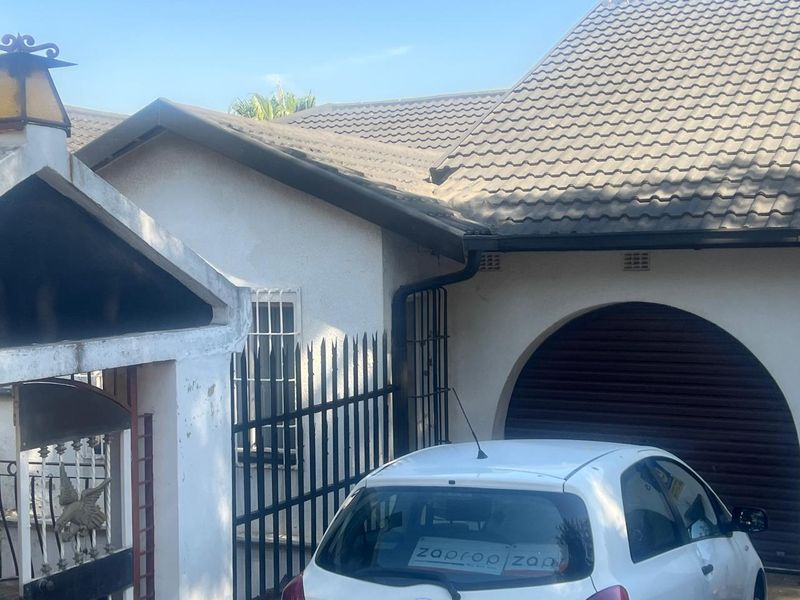 Front exterior view of the house featuring a tiled roof, arched garage entrance, and security fencing.