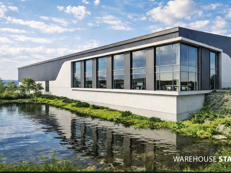 Modern industrial warehouse facility featuring large glass curtain wall windows, sleek metal cladding, and landscaped pond frontage.