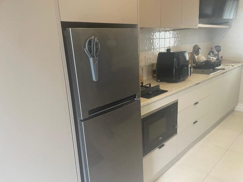 Modern kitchen featuring sleek cabinetry, stone countertops, integrated appliances including a built-in oven and microwave, and a gas hob.