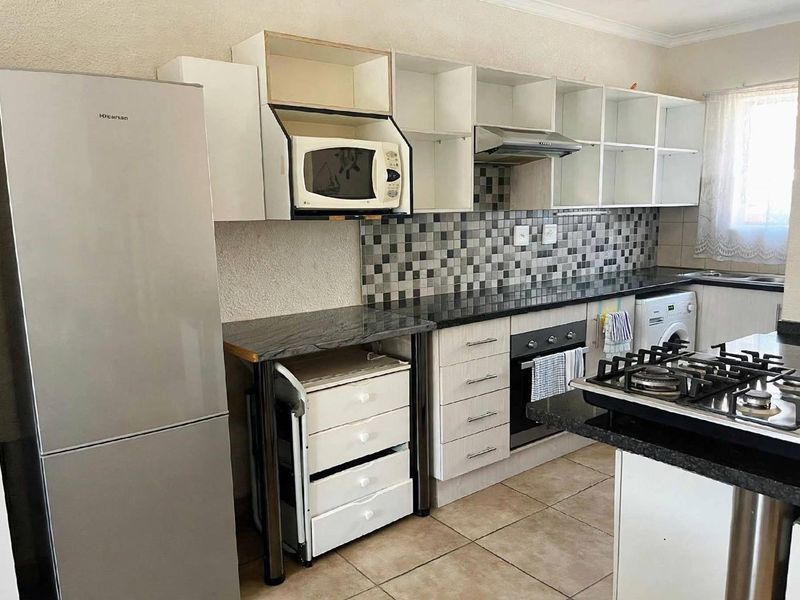 Functional kitchen featuring granite countertops, mosaic tile backsplash, built-in oven, gas hob, and ample cabinetry with some open shelving sections.