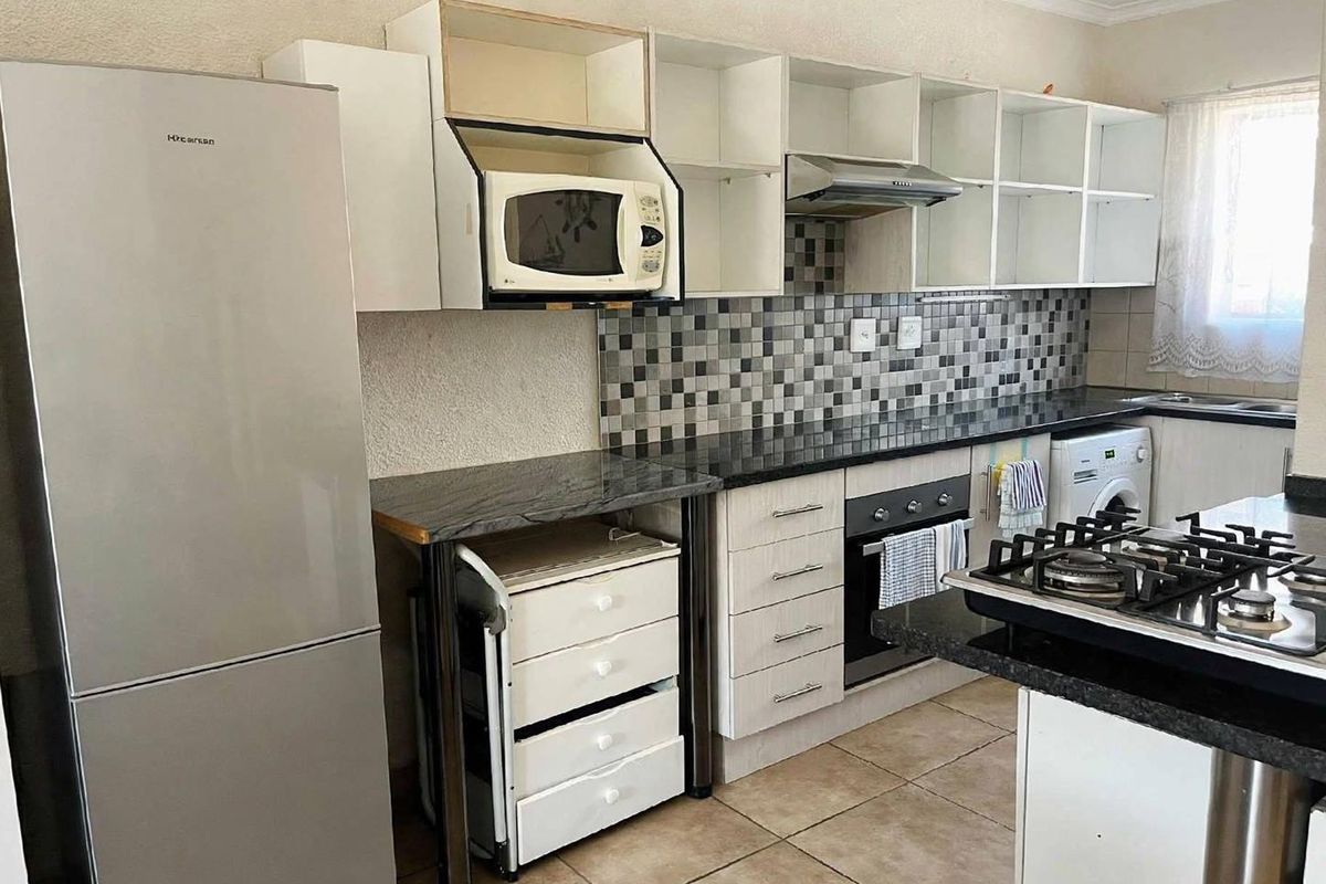 Functional kitchen featuring granite countertops, mosaic tile backsplash, built-in oven, gas hob, and ample cabinetry with some open shelving sections.