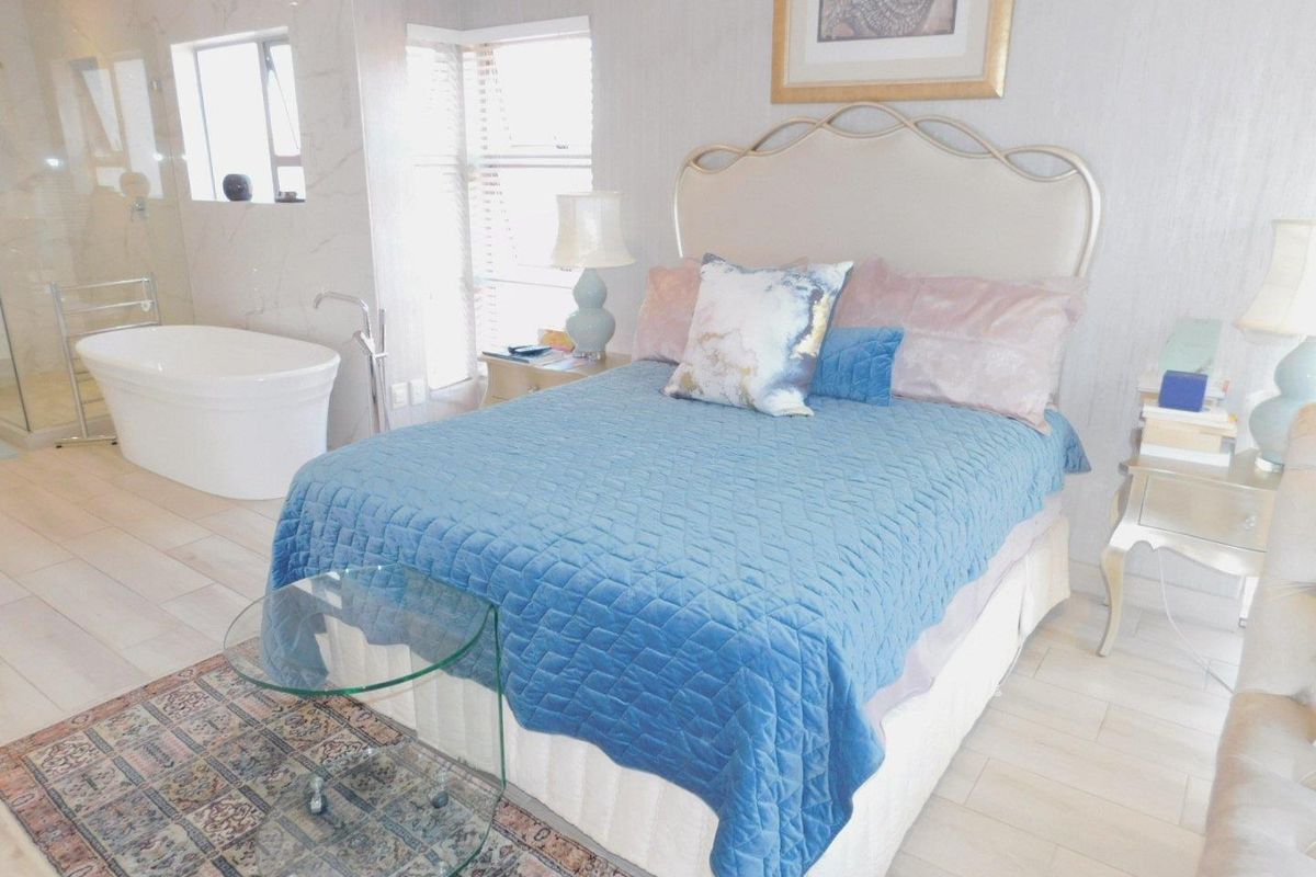 A spacious bedroom featuring an open-plan layout with an integrated en-suite bathroom, including a freestanding bathtub and modern tiled flooring.