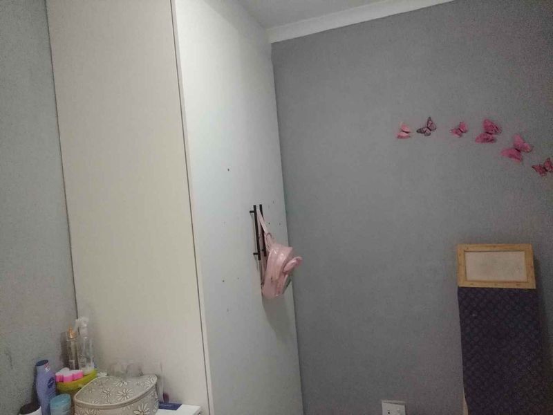 A bedroom featuring a white built-in wardrobe and grey painted walls with decorative wall accents.