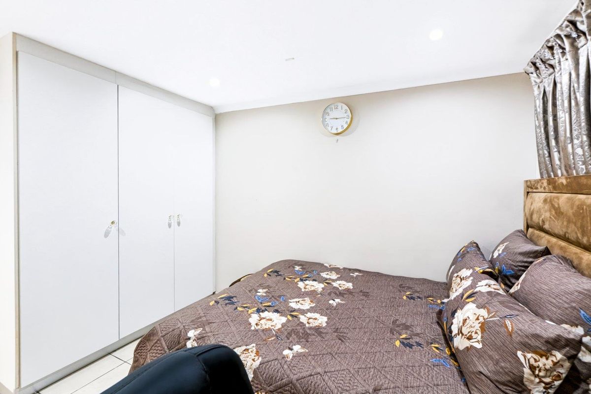 A functional bedroom featuring a built-in wardrobe with white cabinetry and recessed ceiling lighting.
