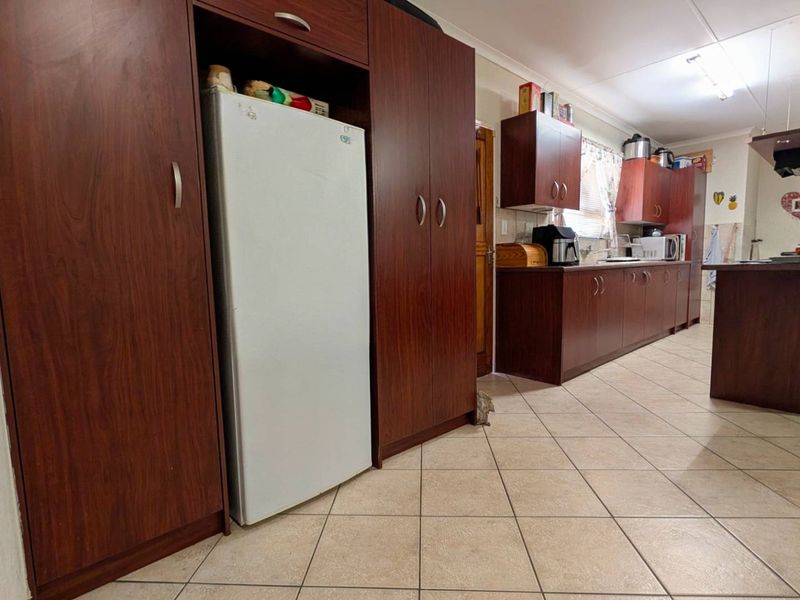 A functional kitchen featuring dark wood cabinetry, tiled flooring, and a central island, offering ample storage and workspace.