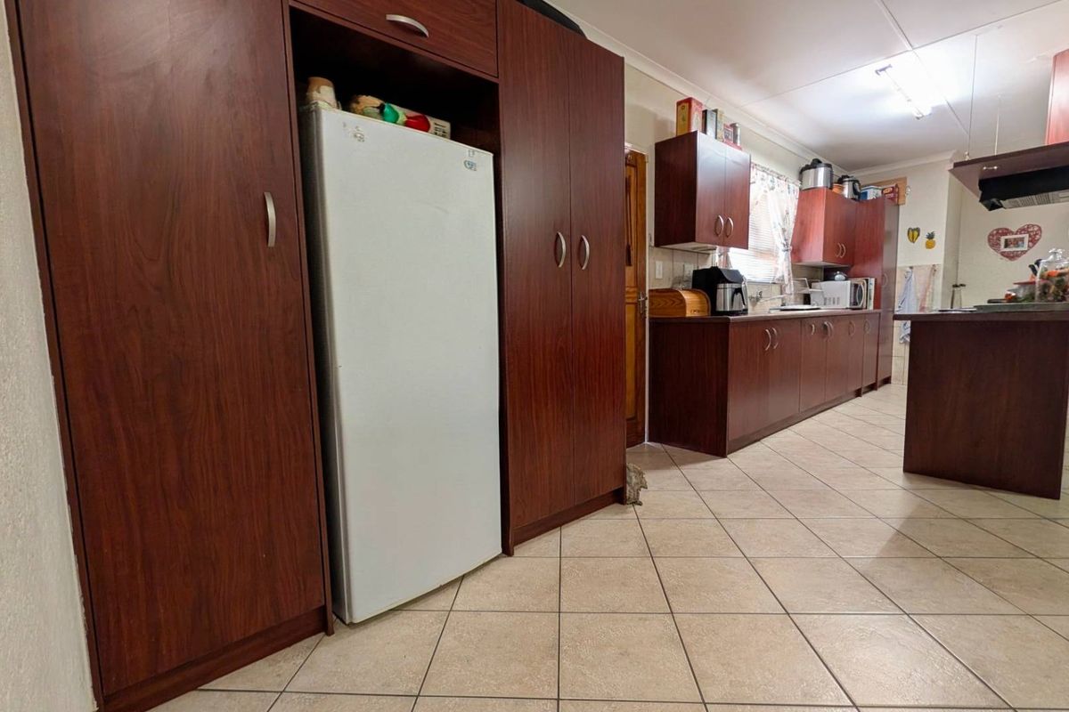 A functional kitchen featuring dark wood cabinetry, tiled flooring, and a central island, offering ample storage and workspace.