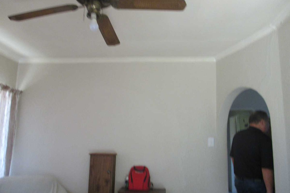 A living room featuring a ceiling fan and a distinctive arched doorway leading to an adjacent space.
