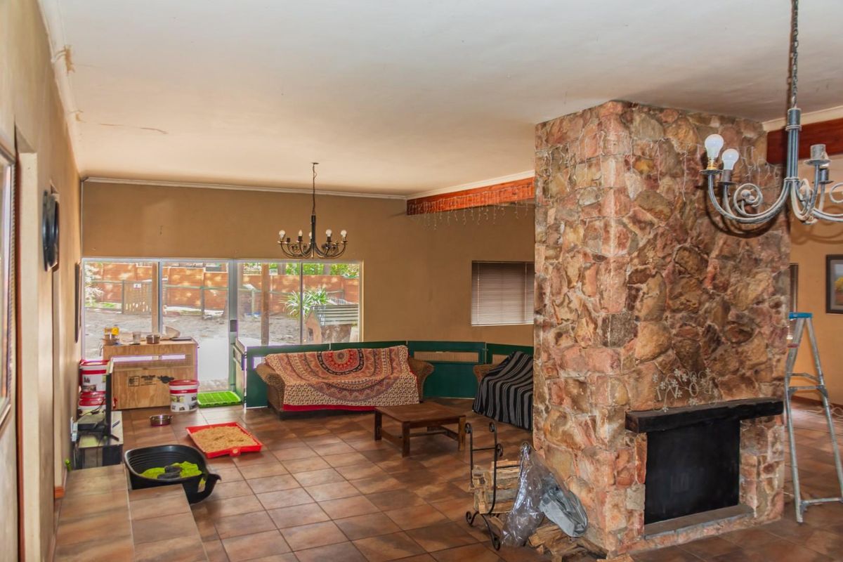 Spacious living room featuring a prominent stone-clad fireplace, tiled flooring, and large sliding glass doors providing access to the rear garden area.