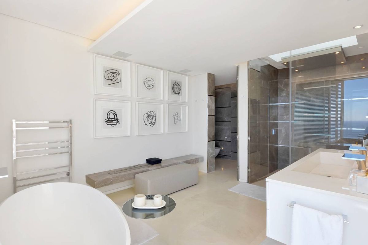 Modern luxury bathroom featuring a freestanding soaking tub, glass-enclosed walk-in shower, stone vanity, and heated towel rail with high-end finishes.