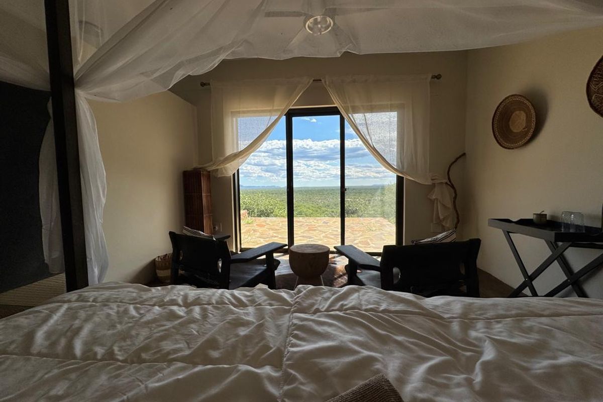 A spacious bedroom featuring a four-poster bed and large sliding glass doors that open onto a private patio with expansive landscape views.
